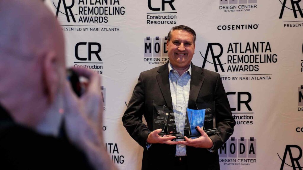 A man proudly holds awards at the Atlanta Awards, celebrating excellence in design and renovation. 